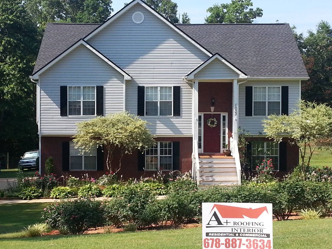 A finished A+ Roofing job: new roof on a two-story home with the A+ yard sign out front